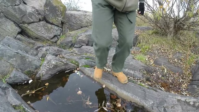Male legs in yellow boots go on  track in hill and rocks. 