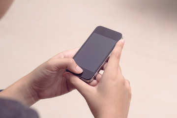 Woman with modern mobile phone in hands touching on a blank scre