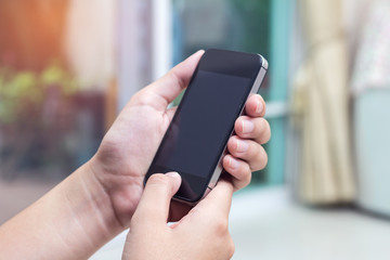 Woman with modern mobile phone in hands touching on a blank scre