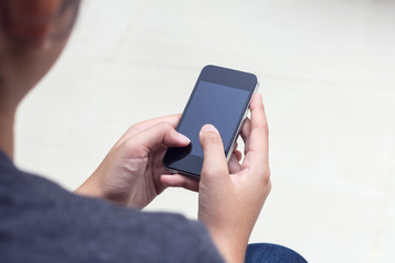 Woman with modern mobile phone in hands touching on a blank scre