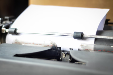 Old typewriter holding blank white paper on office desk with white copy space