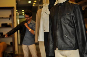 Photograph of beautiful leather jackets with buyer at a leather jacket store. No human figure included in the frame. 