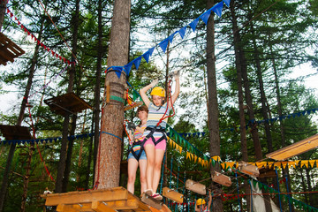 Woman and girl climbing in adventure park
