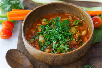 Vegetarian soup in wooden bowl on wood board on white table