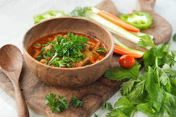 Vegetarian soup in wooden bowl on wood board on white table