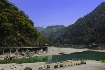 Bridge through the mountain next to green river in China.