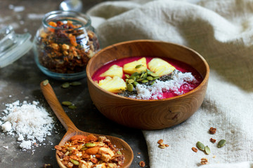 Healthy breakfast with granola and dragon fruit mash in wooden bowl