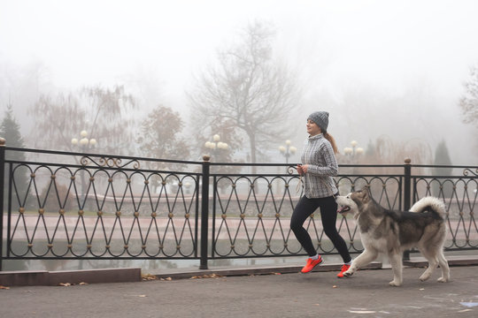 Image of young girl running with her dog, alaskan malamute