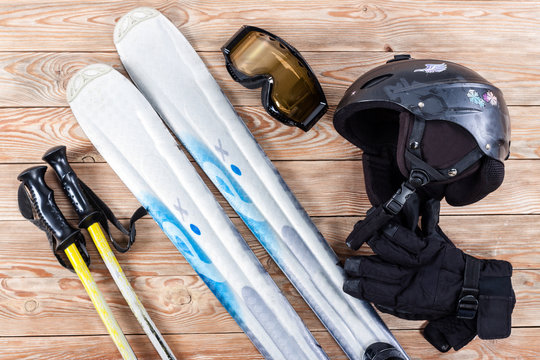 Overhead view of ski accessories placed on rustic wooden table.