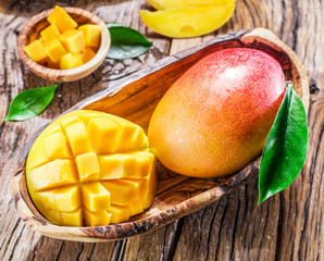 Mango fruit and mango cubes on the wooden table.