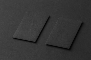 Mockup of two vertical business cards at black textured paper