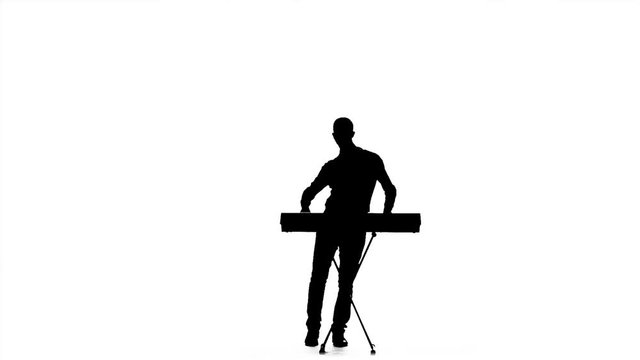 Young man playing on an electronic piano. Silhouette. Slow motion