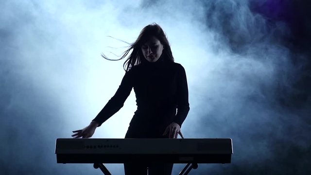 Electronic piano. Woman dancing to music played. Slow motion. Studio