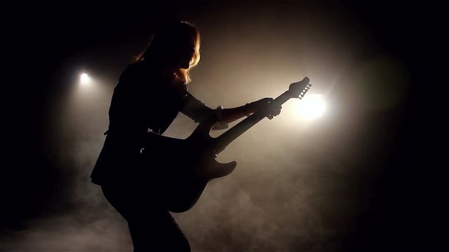 Silhouette Of Woman Playing On Electric Guitar In Smoke And Lights