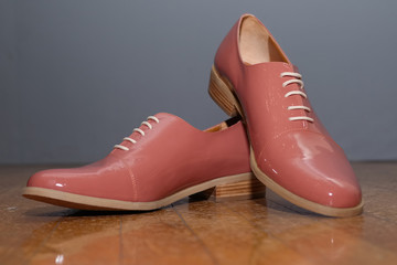 Closeup photo of patent-leather female shoes with laces on woode