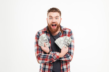 Happy young bearded man in plaid shirt holding dollar bills