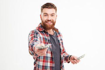 Happy bearded man in plaid shirt giving money on camera