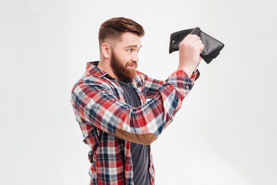 Young man in plaid shirt looking inside his empty wallet
