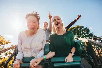 Fotobehang Amusementspark Enthousiaste jonge vrienden rijden pretpark rit