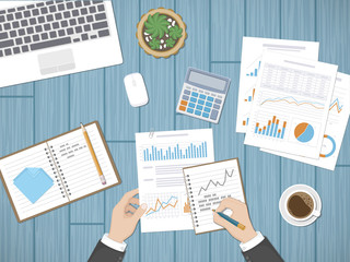 Man analyzes documents. Accounting, analytics, market analysis, report, research, planning concept. Hands on the desktop hold documents. Charts, diagrams, graphs on the paper. Office space top view.