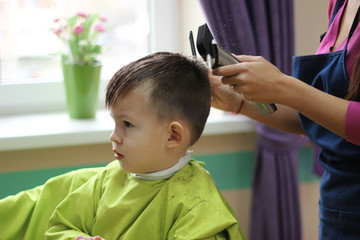 Little boy in hair saloon, haircut, professional barber