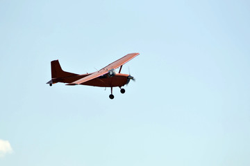 In the sky the small orange plane flies.