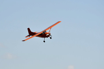 Fototapeta na wymiar In the sky the small orange plane flies.