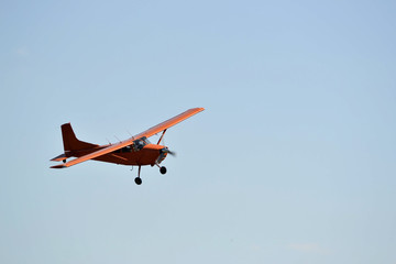 Fototapeta na wymiar In the sky the small orange plane flies.