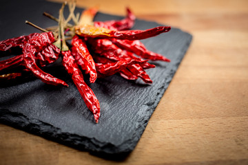 dried red chili pepper on slate on wooden background