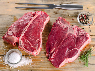 Raw beef steaks on a wooden board.