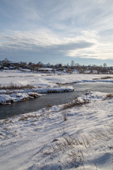Winter landscape, the river and the coast covered with snow, the glare from the sun, the water has not frozen