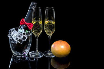 Bottle champagne in ice bucket and wineglasses with grapefruit