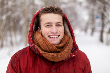 happy man in winter jacket with hood outdoors