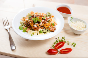 Farfalle with meat, mushrooms, olives and basil on a classic wood. 