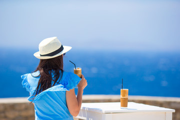 Back view of woman drinking cold coffee enjoying sea view. Beautiful woman relax during european...