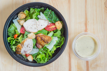 Organic mixed green salad with chicken in a transparent plastic plates on  wooden table very tasty