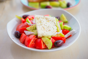 Delicious fresh greek salad served for lunch at outdoor restaurant with beautiful view on the sea and port