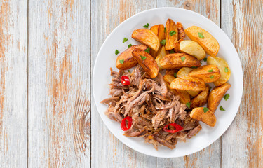 pulled slow-cooked meat roasted in oven with fried potato