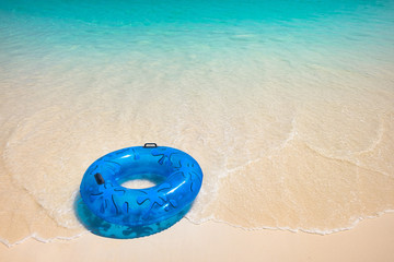 Fototapeta na wymiar Blue Life Buoy on the White Beach with Emerald Sea in Summer