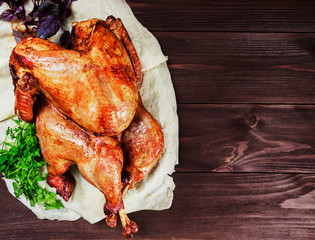 Roasted Turkey. Thanksgiving table served with turkey, decorated with greens and basil on dark wooden background. Homemade roasted chicken. Christmas holiday dinner. Top view