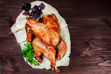 Roasted Turkey. Thanksgiving table served with turkey, decorated with greens and basil on dark wooden background. Homemade roasted chicken. Christmas holiday dinner. Top view
