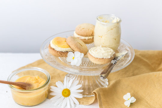Pots of homemade lemon curd, buttercream and Shortbread biscuits sandwiched with lemon icing (Lemon Melting Moments) on a cakestand