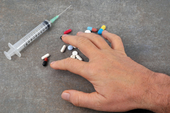 Main posée sur des médicaments près d'une seringue