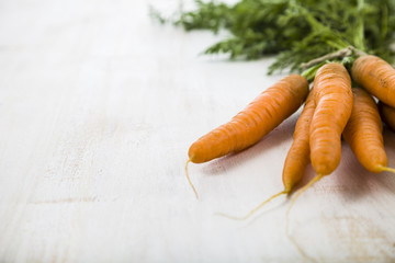 Ripe red carrots with leaves on a wooden table close-up. Fresh v
