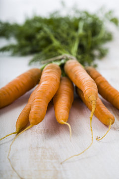 Ripe red carrots with leaves on a wooden table close-up. Fresh v