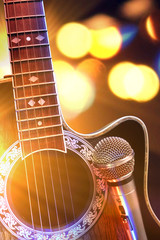 Acoustic guitar and microphone with lights in the background