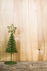 Christmas tree on a wooden background. Green metal decorative tr