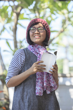 asian woman holding open booket book in hand and toothy smiling