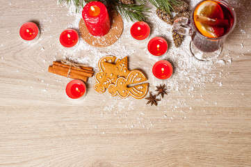 Mulled wine with lemon and cinamon sticks in glass and christmas cookies on the wooden table with christmas tree branch, snow and Christmas card or letter with free space for text