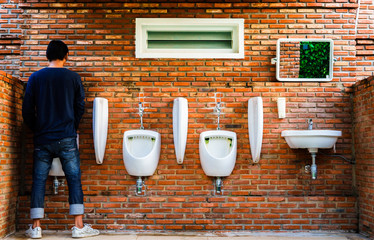 Man standing pee Brick wall public toilet exterior / outdoor